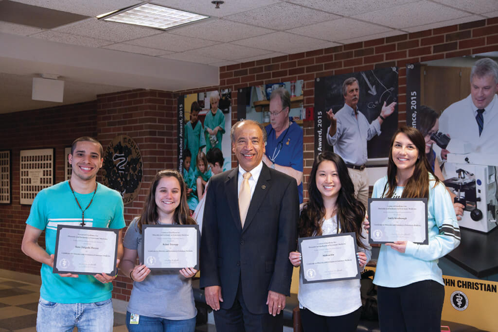 Dean Reed stands alongside students smiling and holding up their certificate of completion