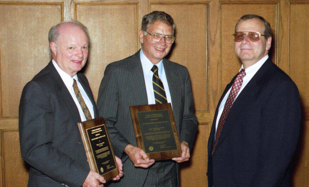 Dr. Parker and Dr. McKibben hold their award plaques and then Dean Al Rebar smiles beside them