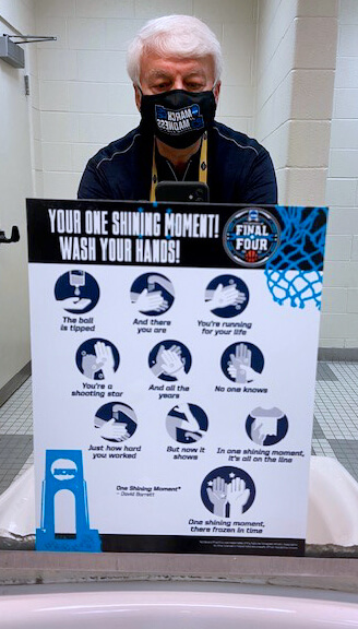 Dr. Borst takes a snapshot of a handwashing sign at a bathroom sink