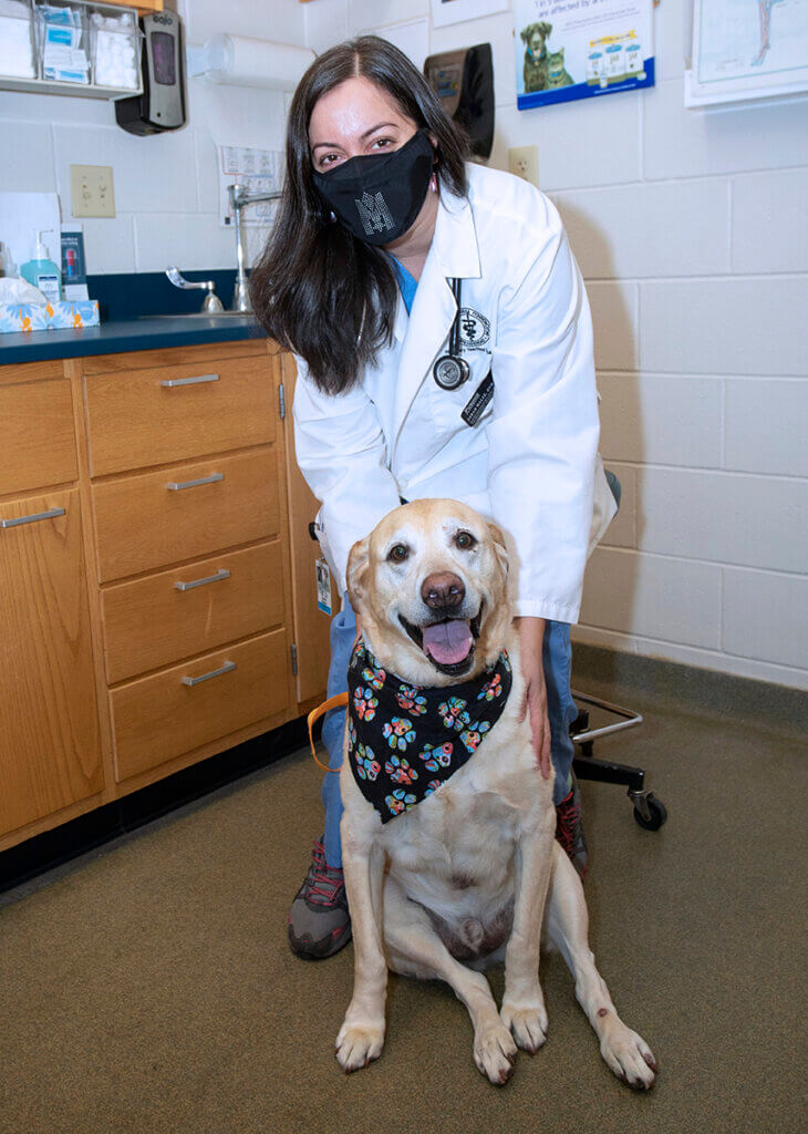 Cooper sits in an exam room along with Dr. Sarah Malek who sits behind him touching his shoulder.