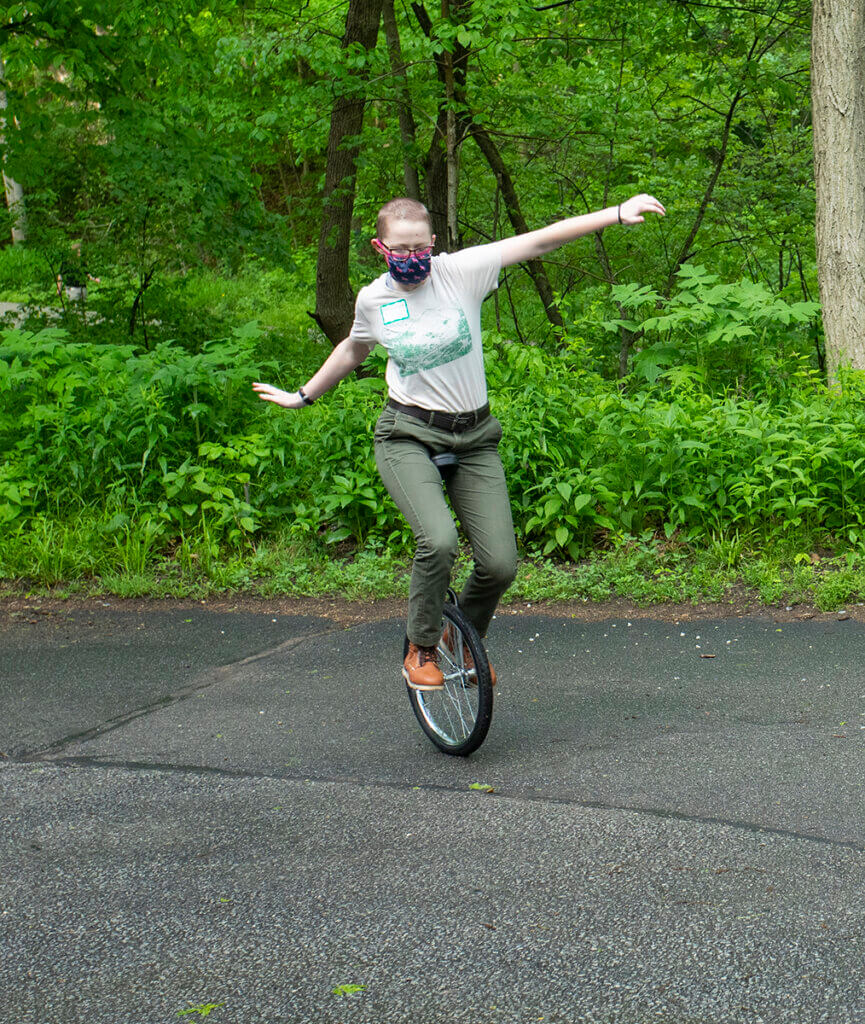 Keely balances on the unicycle with her arms stretched out