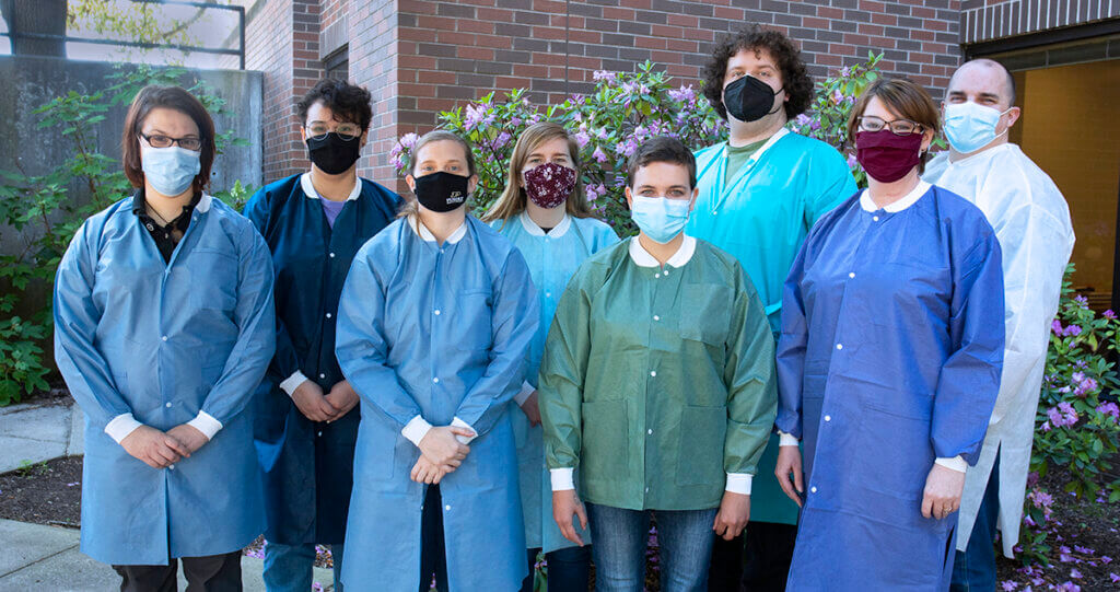 The Molecular Laboratory team gathered together for a group photo in the courtyard donning lab coats and face masks