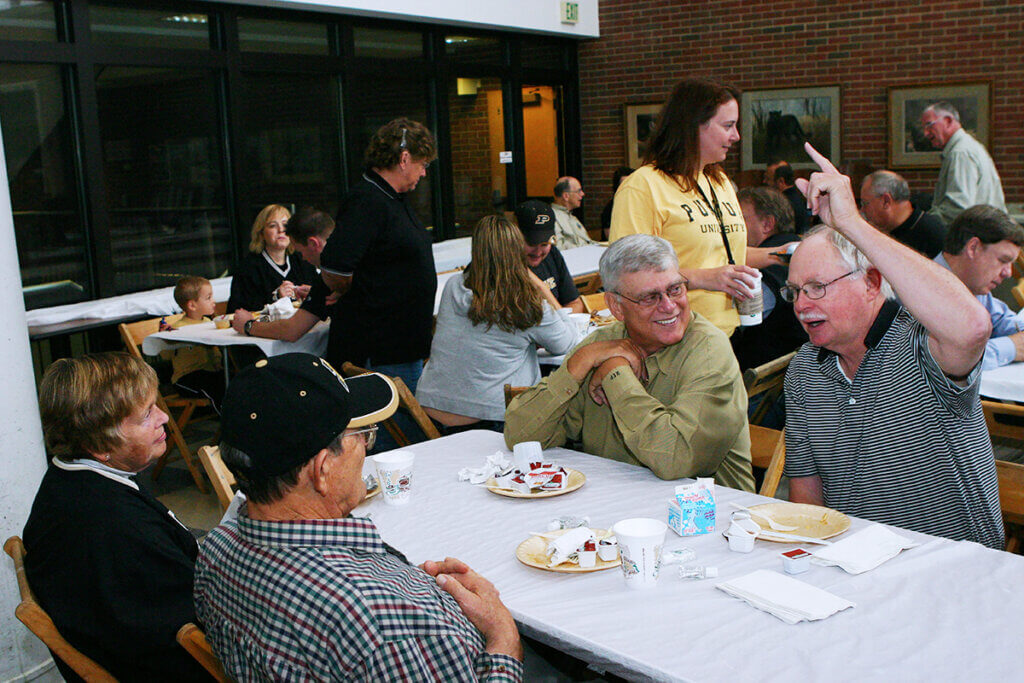 Dr. Ferguson raises his finger in the air engaged in conversation with fellow classmates seated at the table after breakfast