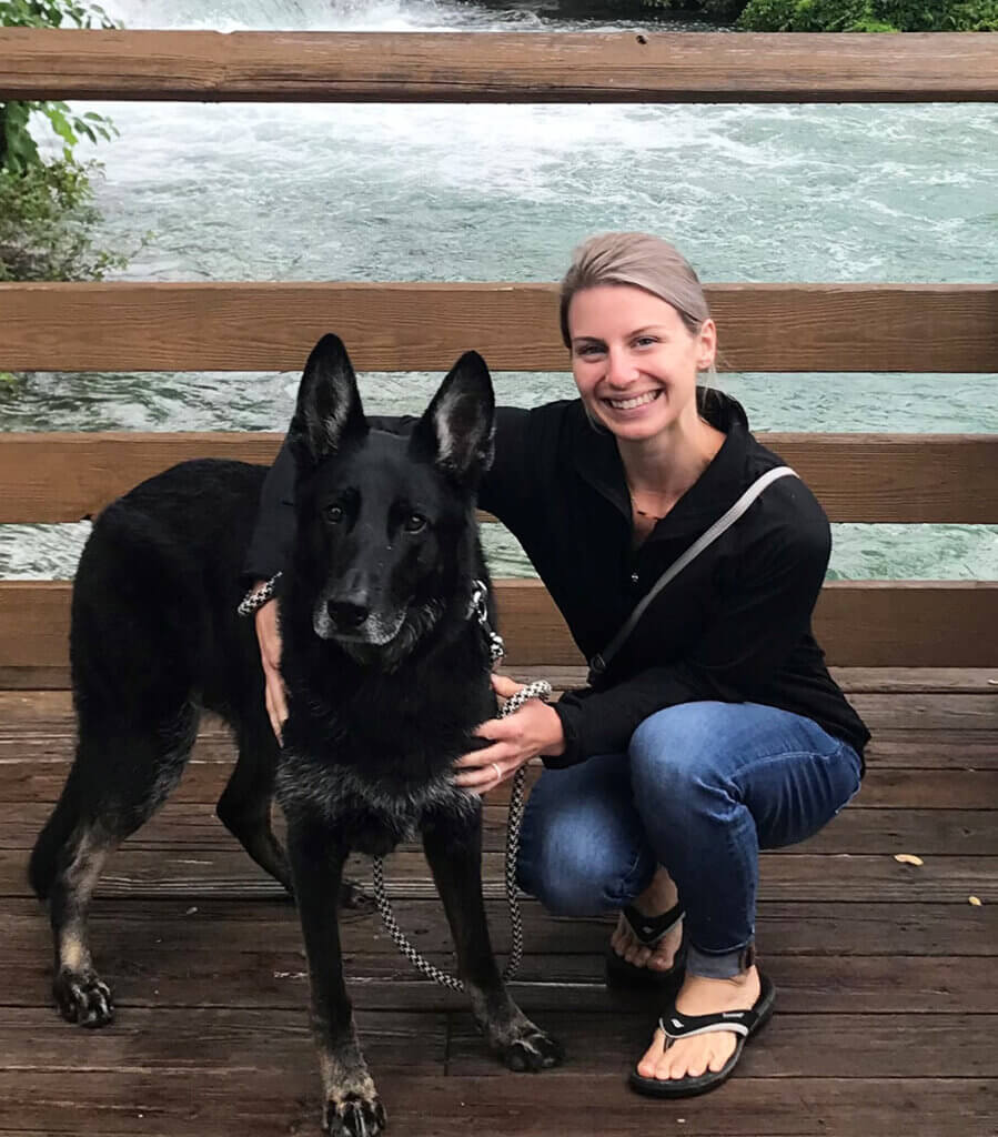 Portrait of Carissa smiling with her dog, a black German Shepard
