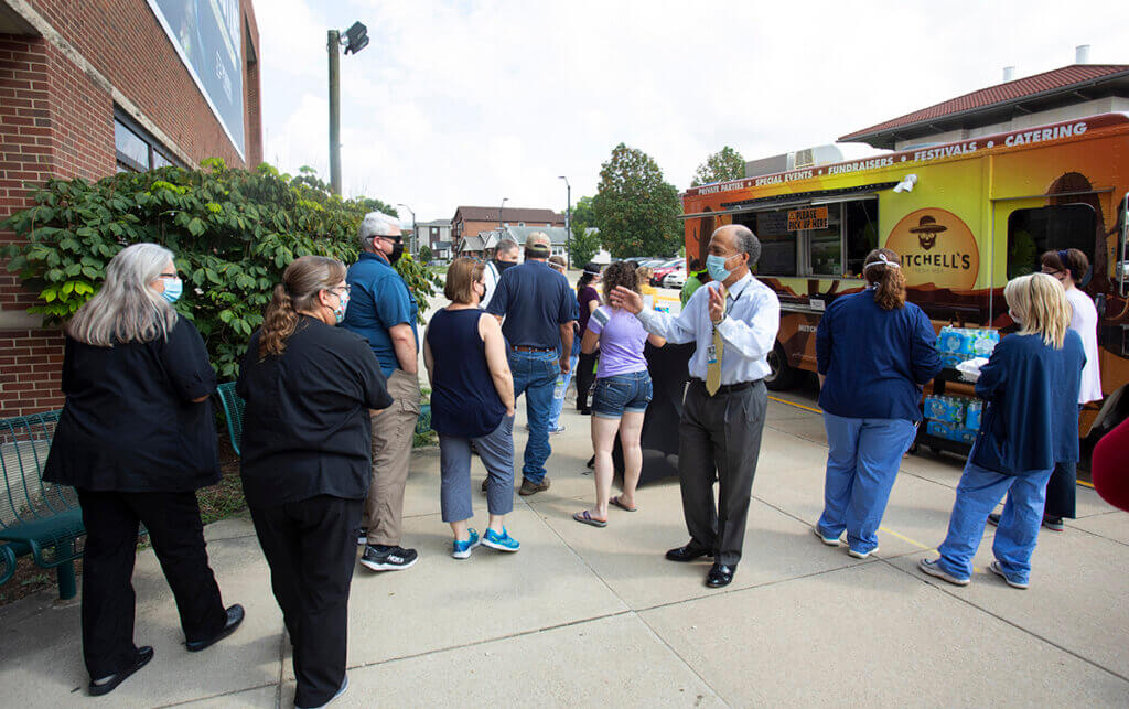 Dean Reed welcomes faculty and staff as they wait in line for the food truck