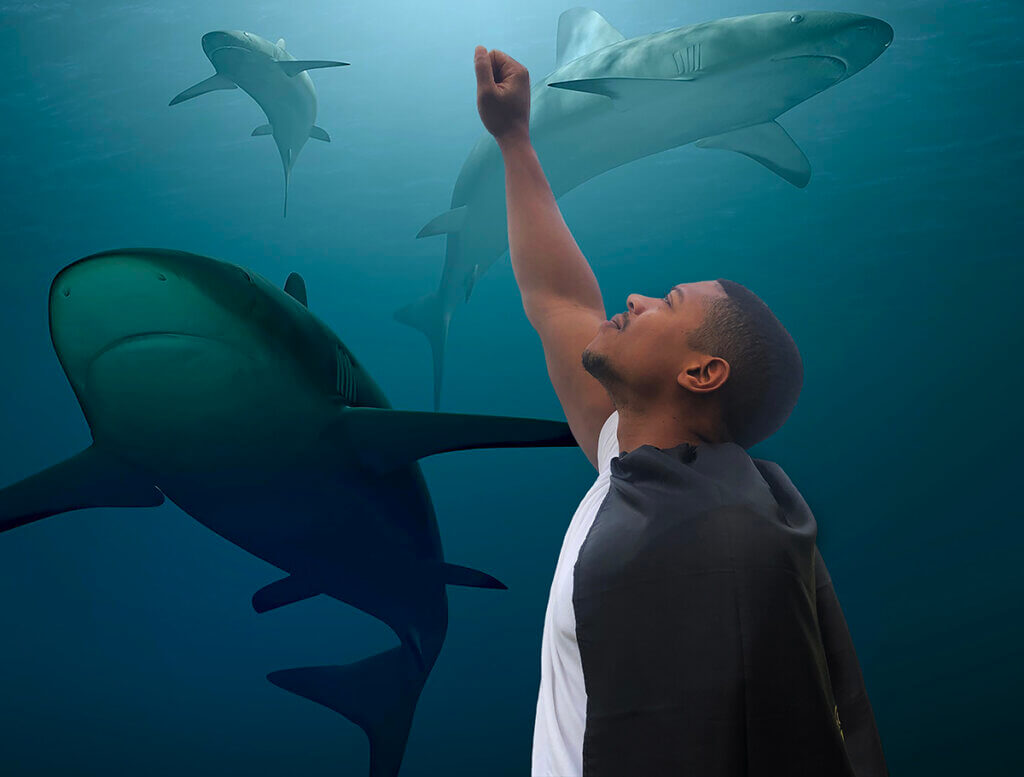 Dr. Vacques Hines "Megalodon" strikes a superhero pose against a background of sharks swimming in the ocean
