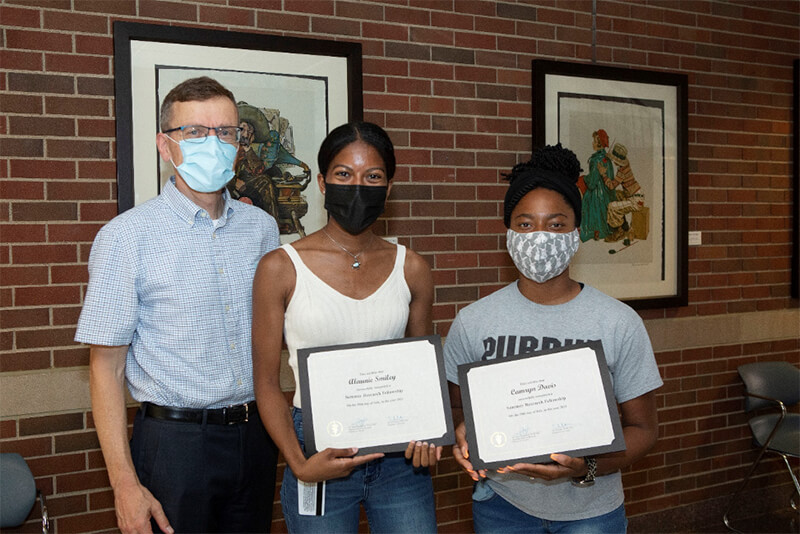 Associate Dean HoegenEsch with students Smiley and Davis holding their diplomas