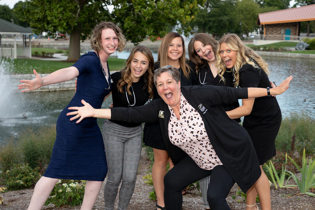 veterinary nursing students smile wearing their new stethoscopes as Paige jumps in front with her arms open wide