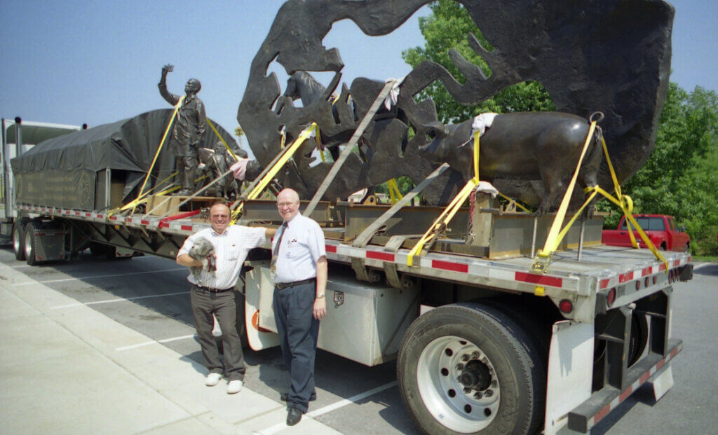 Dr. Buening and Ken stand against the flatbed of the semi carrying the Continuum sculpture pieces.