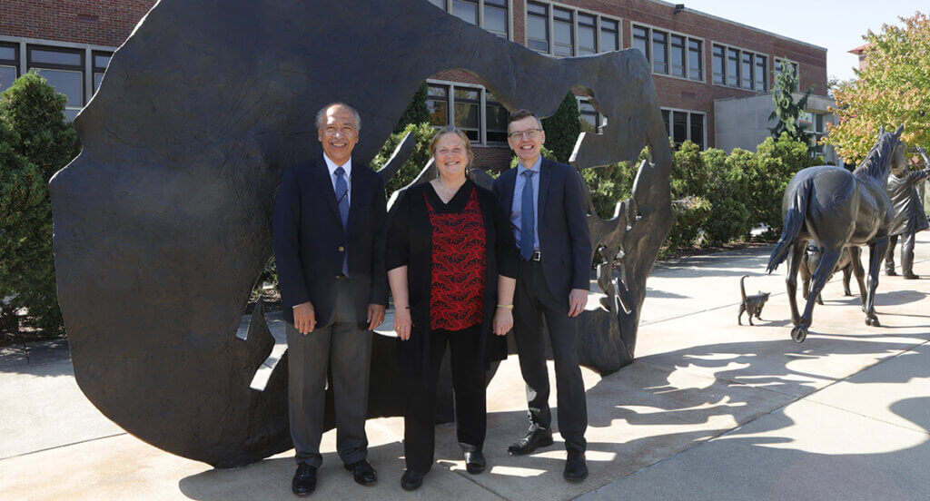Dean Reed, Dr. Vincent, and Dr. HogenEsch stand smiling against the Continuum sculpture backdrop in front of Lynn Hall