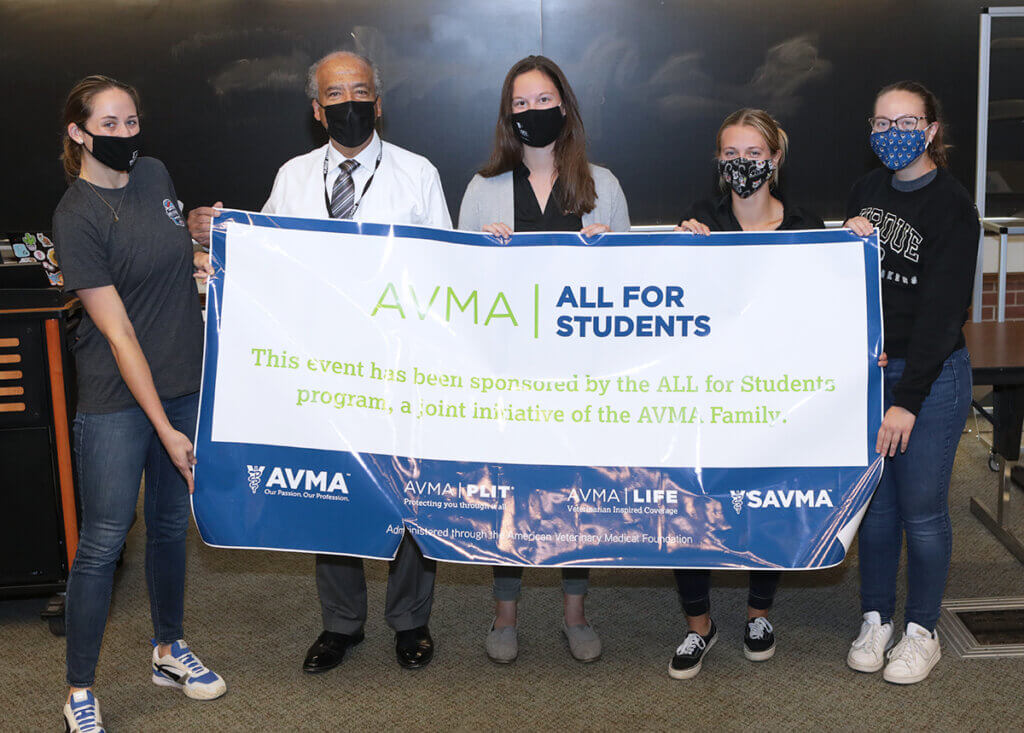 Dean Reed and students stand behind a large banner sign recognizing the AVMA All for Students program