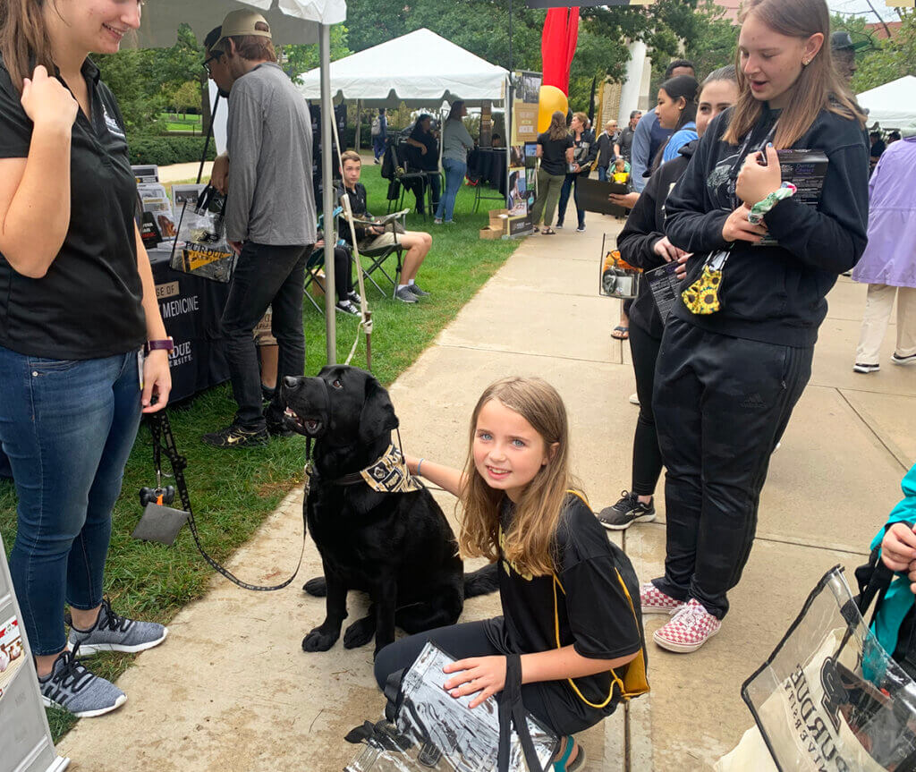 Bethany kneels down to pet Finn as she looks toward the camera smiling