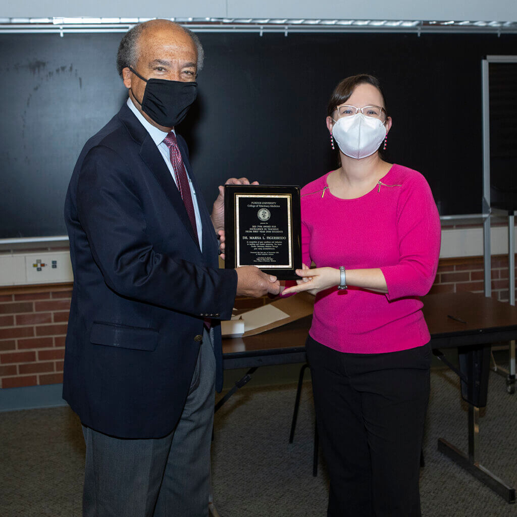 Dean Reed and Dr. Figueiredo stand together holding up her plaque