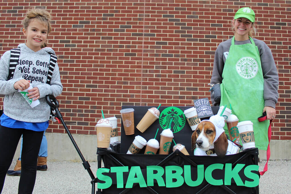 Otis sits in a decorated wagon with the help of his coffee loving helpers