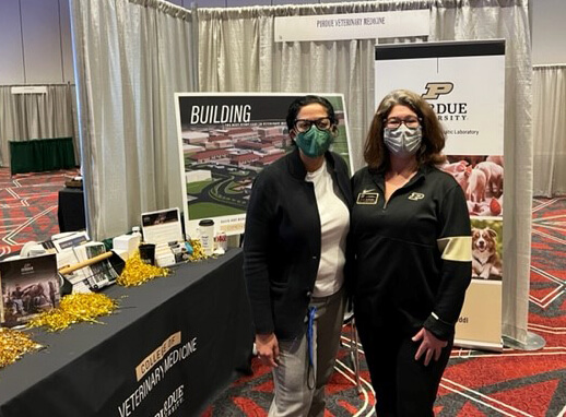 Leslie and Susan stand beside the PVM booth in the conference exhibit hall