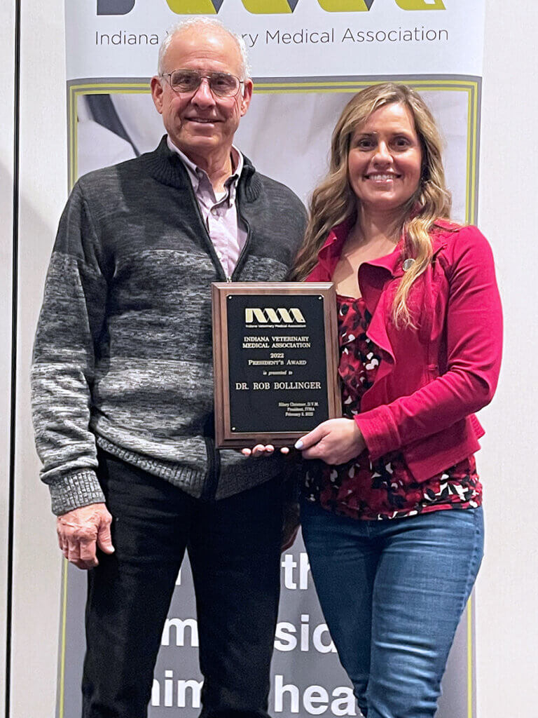 Dr. Bollinger and Dr. Christner stand together holding up his plaque smiling at the camera