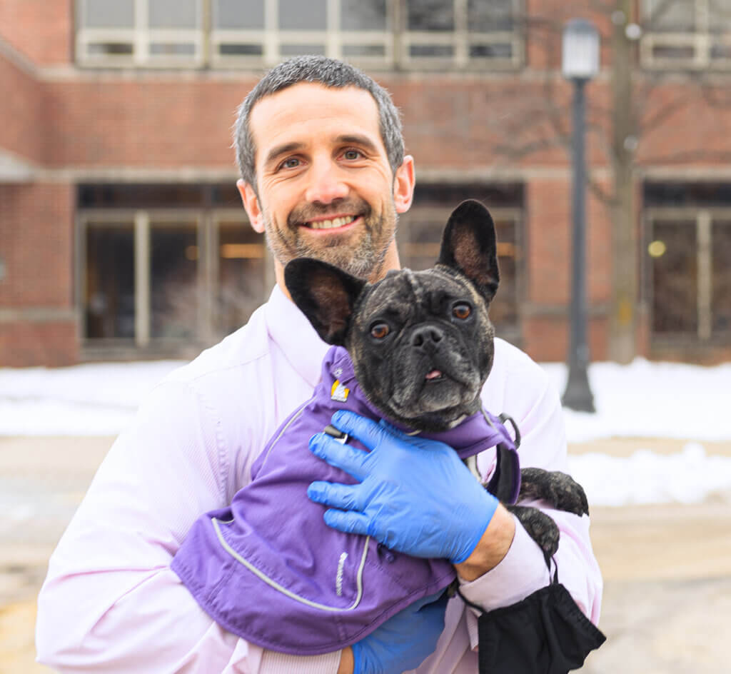 Dr. Bentley holds Dakota who wears a jacket to fend of the cold snowy weather