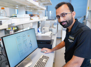 Dr. Verma pictured in front of a computer in his lab