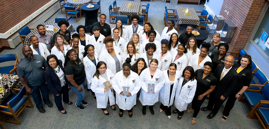 the group smiles up at the camera for a group photo in the library during the celebration