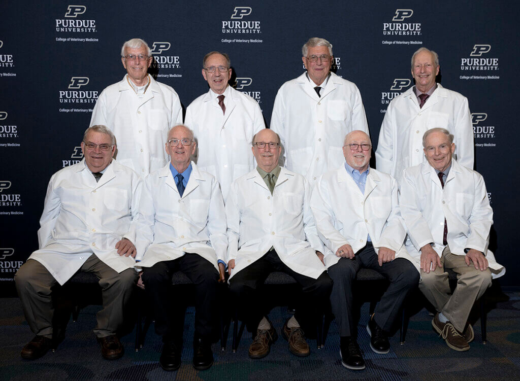 Alumni in the DVM Class of 1971 don white coats and join together for a group photo