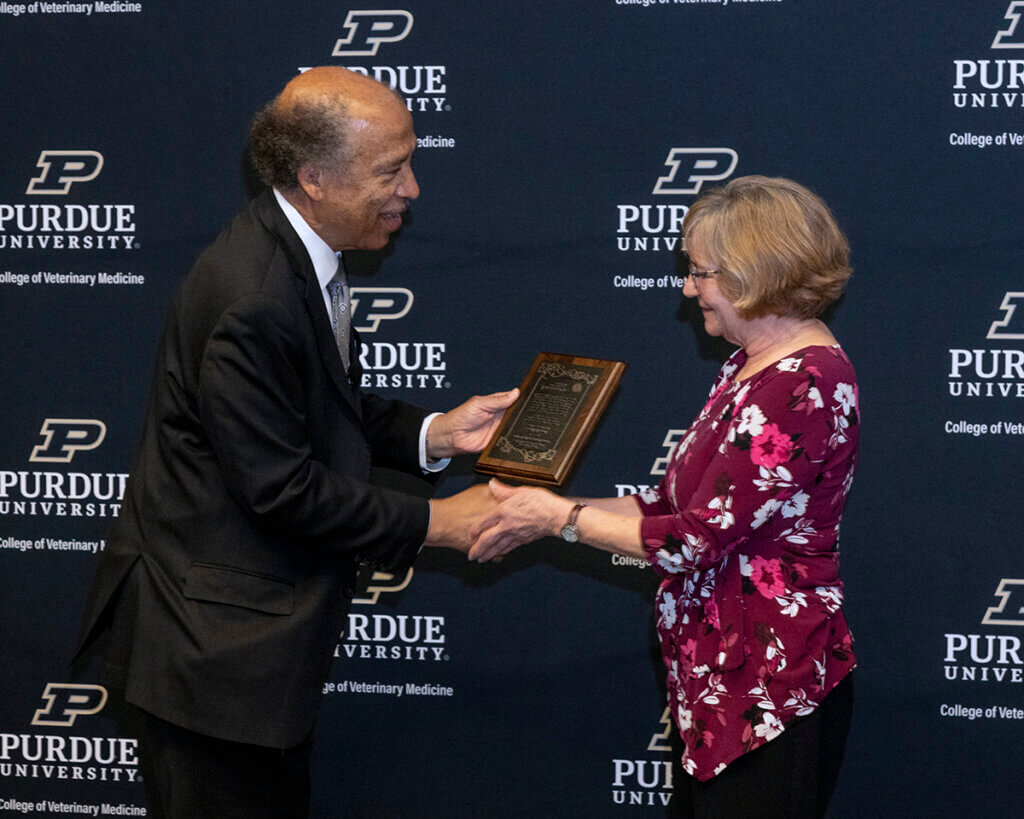 Janet shakes Dean Reed's hand as he hands Janet her award plaque