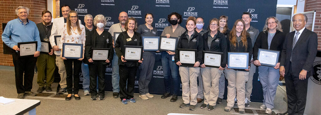 Bravo Award winners are joined by Dean Reed for a group photo as they smile holding up their award certificates