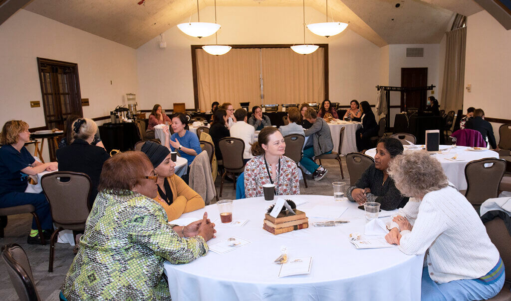 Faculty participants sit at tables engaged in conversation