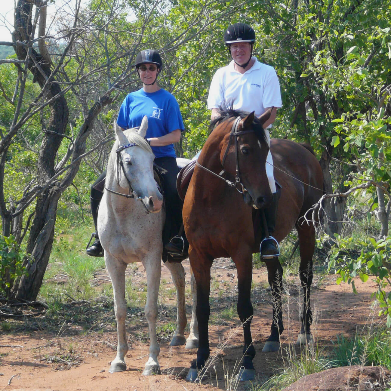 Brenda and John pause sitting atop their horses on a trail
