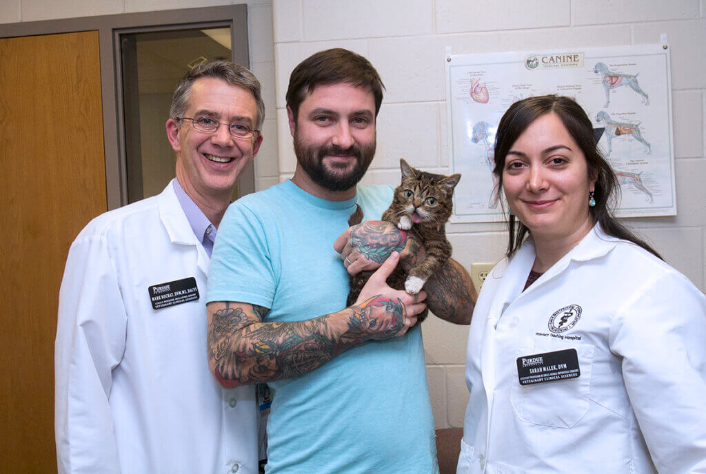 Mike holds up Lil BUB as Drs. Rochat and Malek stand on either side in the Small Animal Hospital