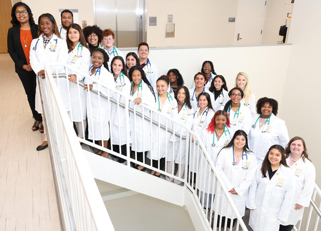 Dr. Craig and Vet Up! participants line up on the stairs and smile for a group photo