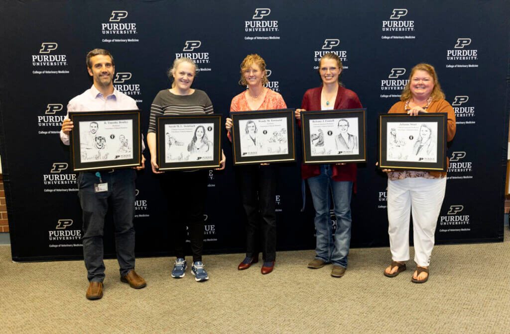 Recently promoted faculty members (left-right) Dr. Tim Bentley, Dr. Sarah Steinbach, Dr. Wendy Townsend, Dr. Bethany Funnell and Dr. Julianne Stout holding their hand-drawn portrait illustrations commemorating the occasion.