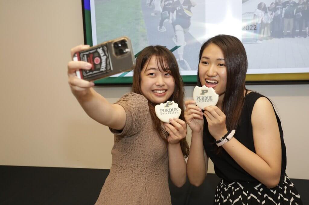 Kitasato students Yuri Yoshimura and Haruna Satomi catch a selfie “worth a thousand words” as they enjoy Purdue University branded cookies.