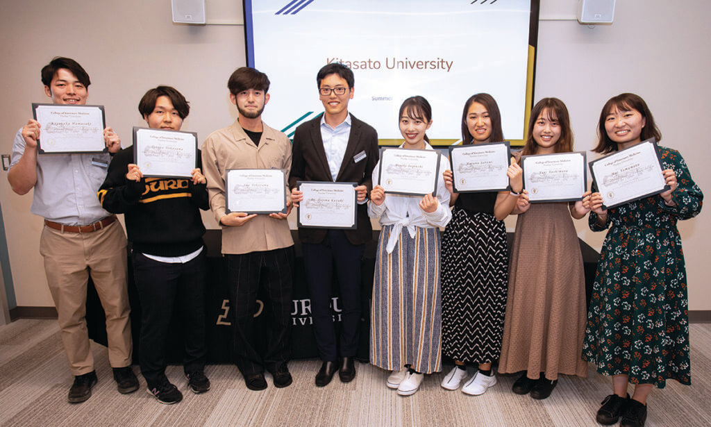 Kitasato visitors smile and hold up certificates