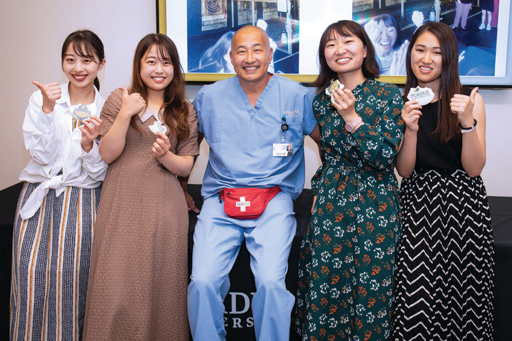 Kitasto visitors join Dr. Inoue for a group photo holding up half eaten Purdue branded cookies