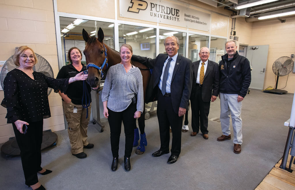 The group stands in the treadmill room of the center around Leila the horse