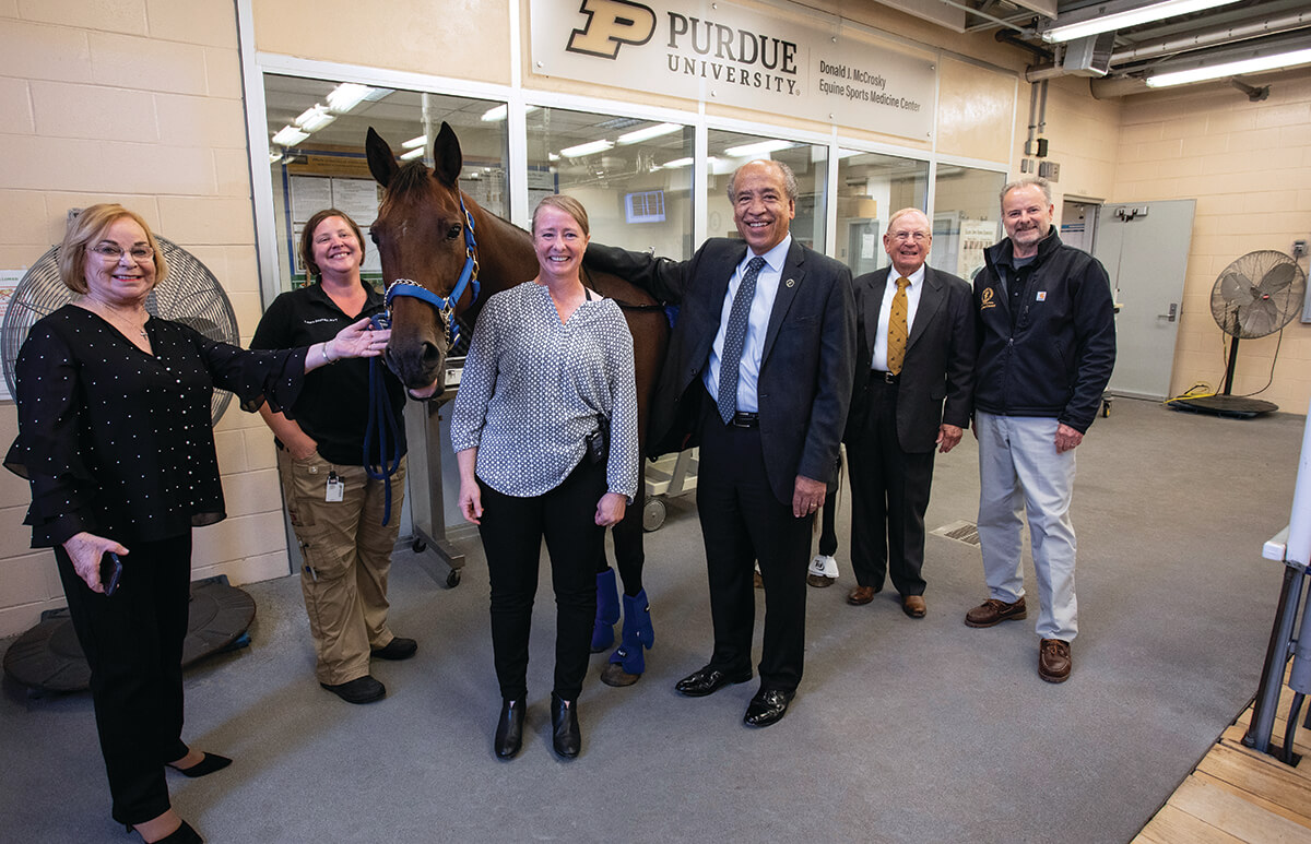 The group stands in the treadmill room of the center around Leila the horse