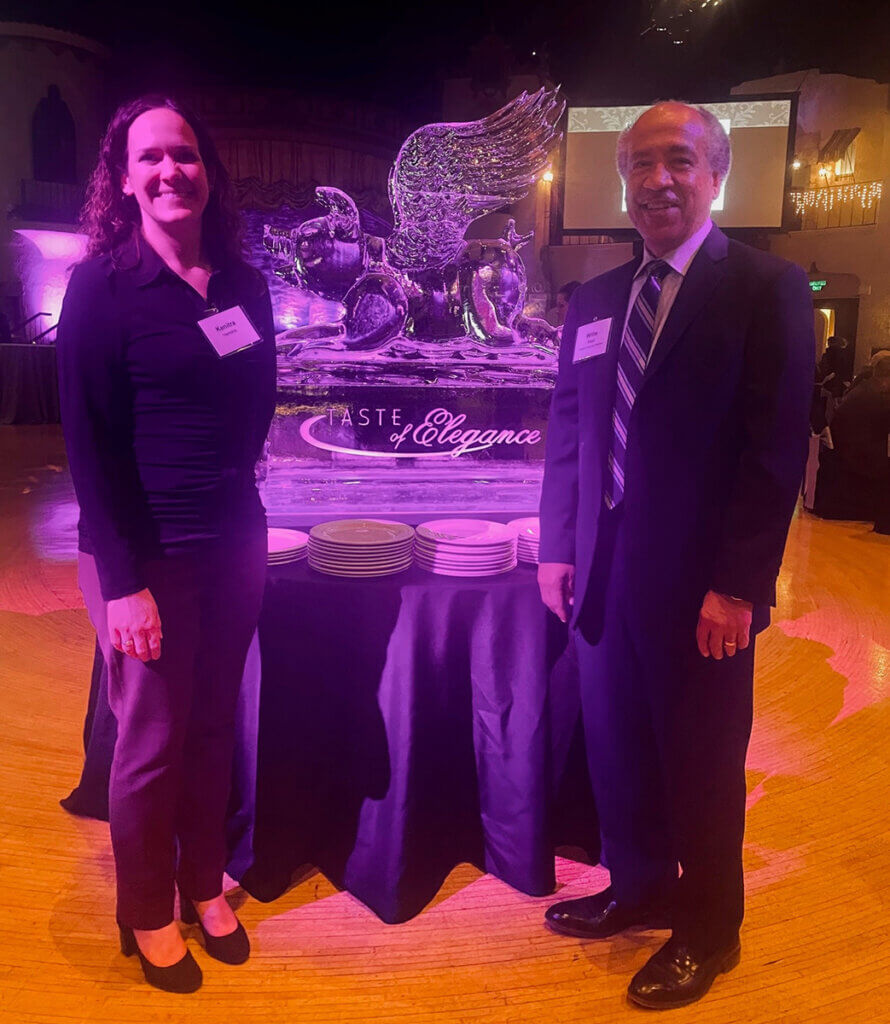Dr. Hendrix and Dean Reed stand in front of an ice sculpture of a flying pig at the event
