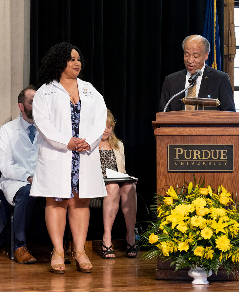 Avery listens to the dean as she accepts her award onstage during the White Coat Ceremony