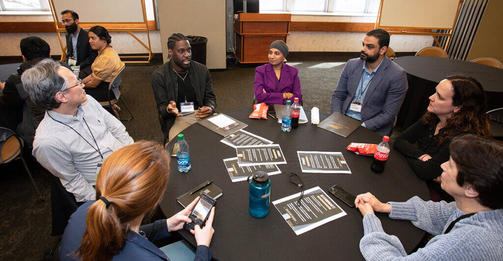 A group of conference attendees engage in conversation around a table in Stewart Center