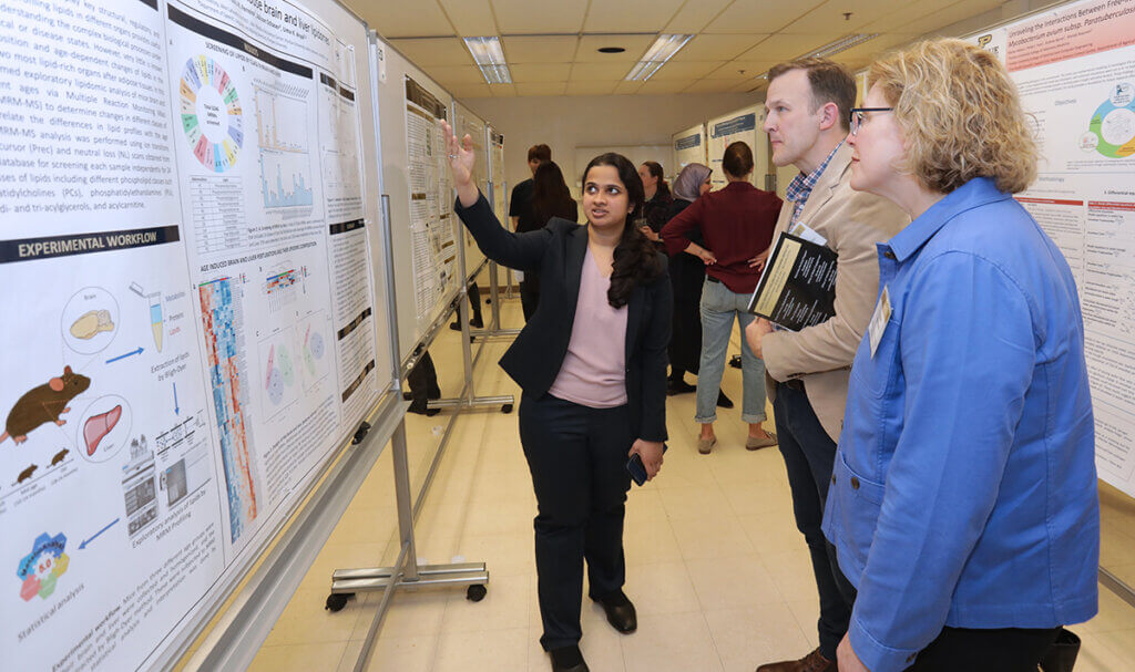 A student speaks with industry representatives visiting her poster display