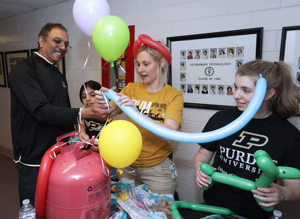Dr. Narayanan helps a student create a balloon animal