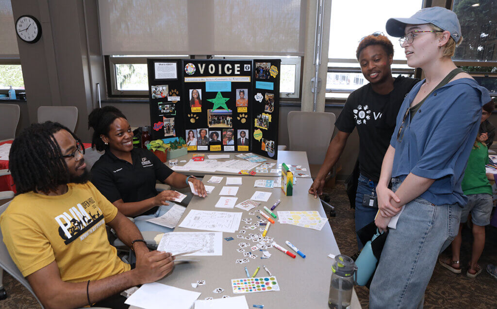 Students smile as they talk at the VOICE exhibit