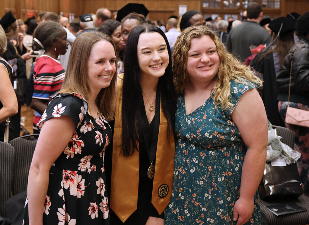 Traci, Anastasia, and Samantha smile for a photo during the reception as part of the college's graduation celebration