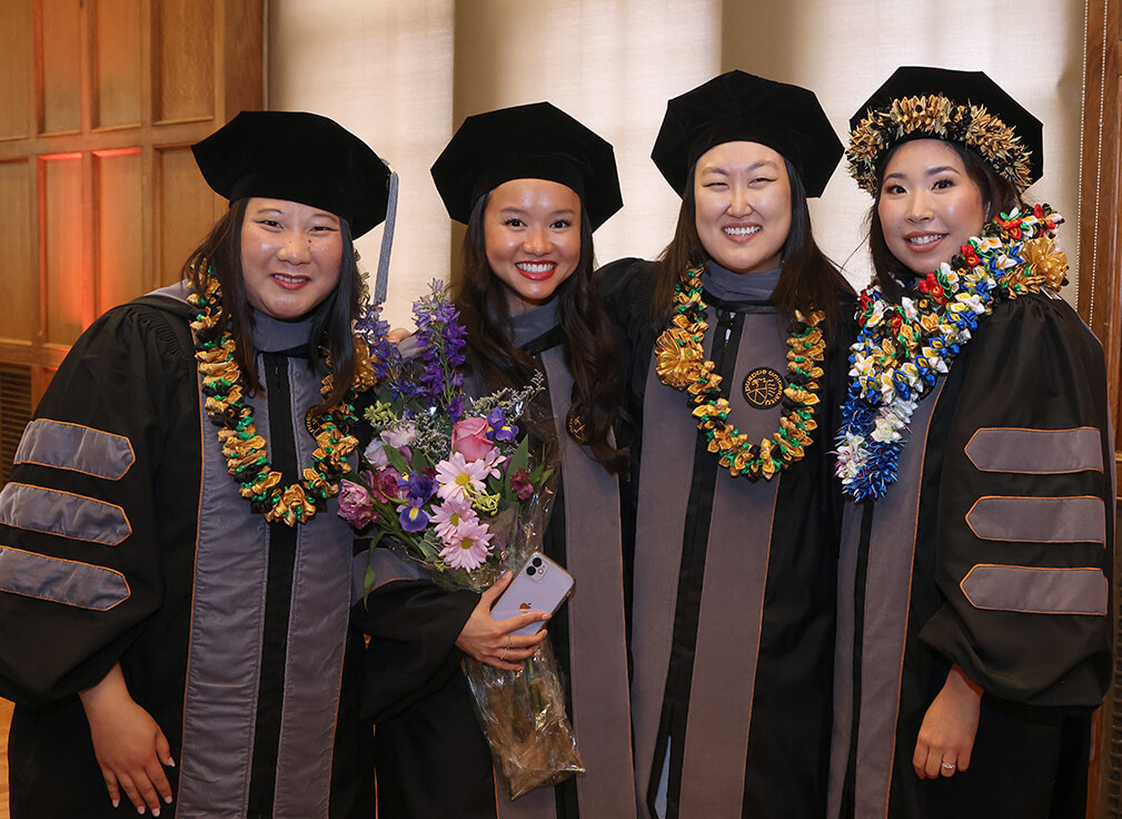 The graduates join together smiling with some wearing leis, which are a symbol of good luck