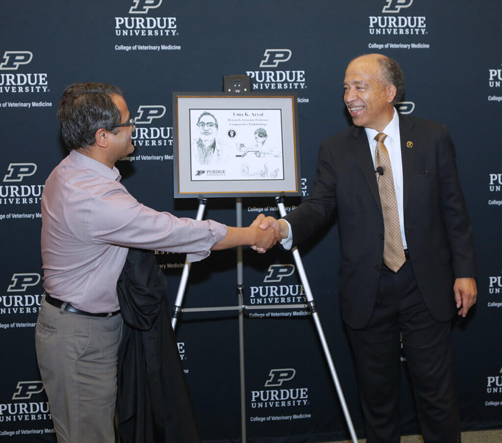 Dr. Aryal shakes Dean Reeds hand after unveiling his portrait gift.