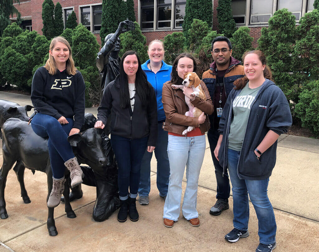 Dr. Ekenstedt and her lab team gather around the Continuum sculpture outside Lynn Hall