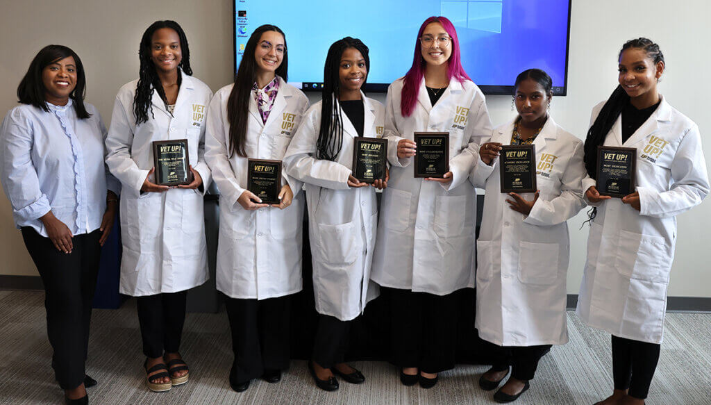 Marsha joins awardees as they pose with their award plaques wearing their Vet Up! white coats during the reception