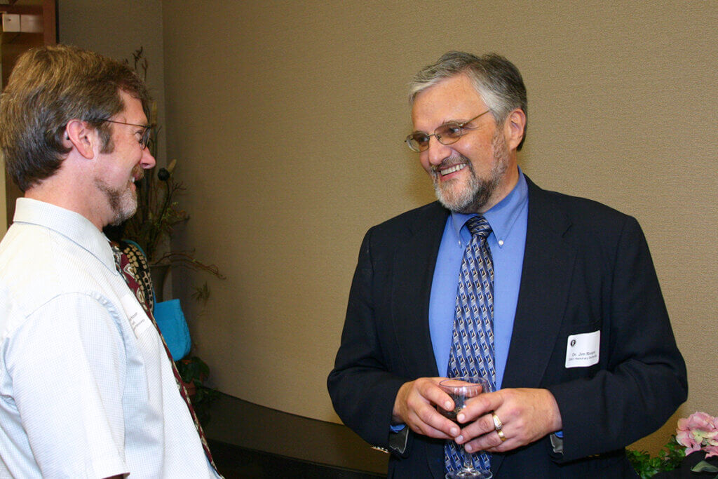 Drs. Hoover and Riviere stand opposite each other smiling engaged in conversation