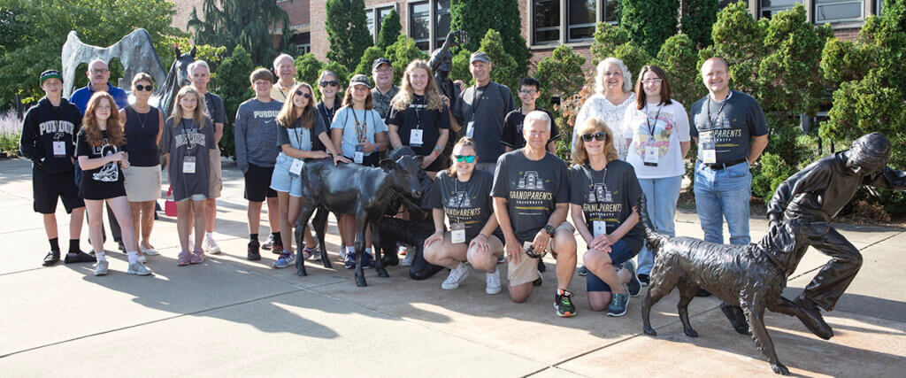 The group takes a photo along with Dr. Chad Brown alongside the bronze sculpture in front of Lynn Hall