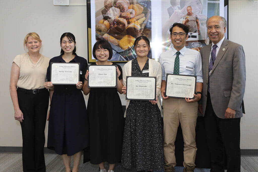 Rakuno Gakuen visitors hold up their exchange program completion certificates as their joined by Dean Reed and Dr. Salisbury